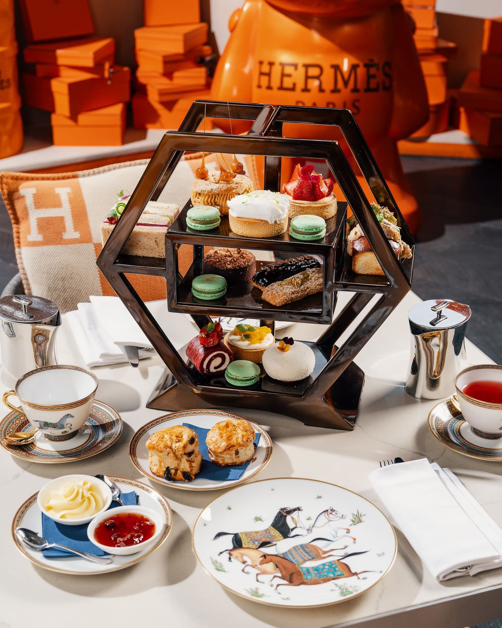 Afternoon tea at ZENON: a tiered stand of pastries and macarons, scones with cream and jam, and porcelain painted with horses