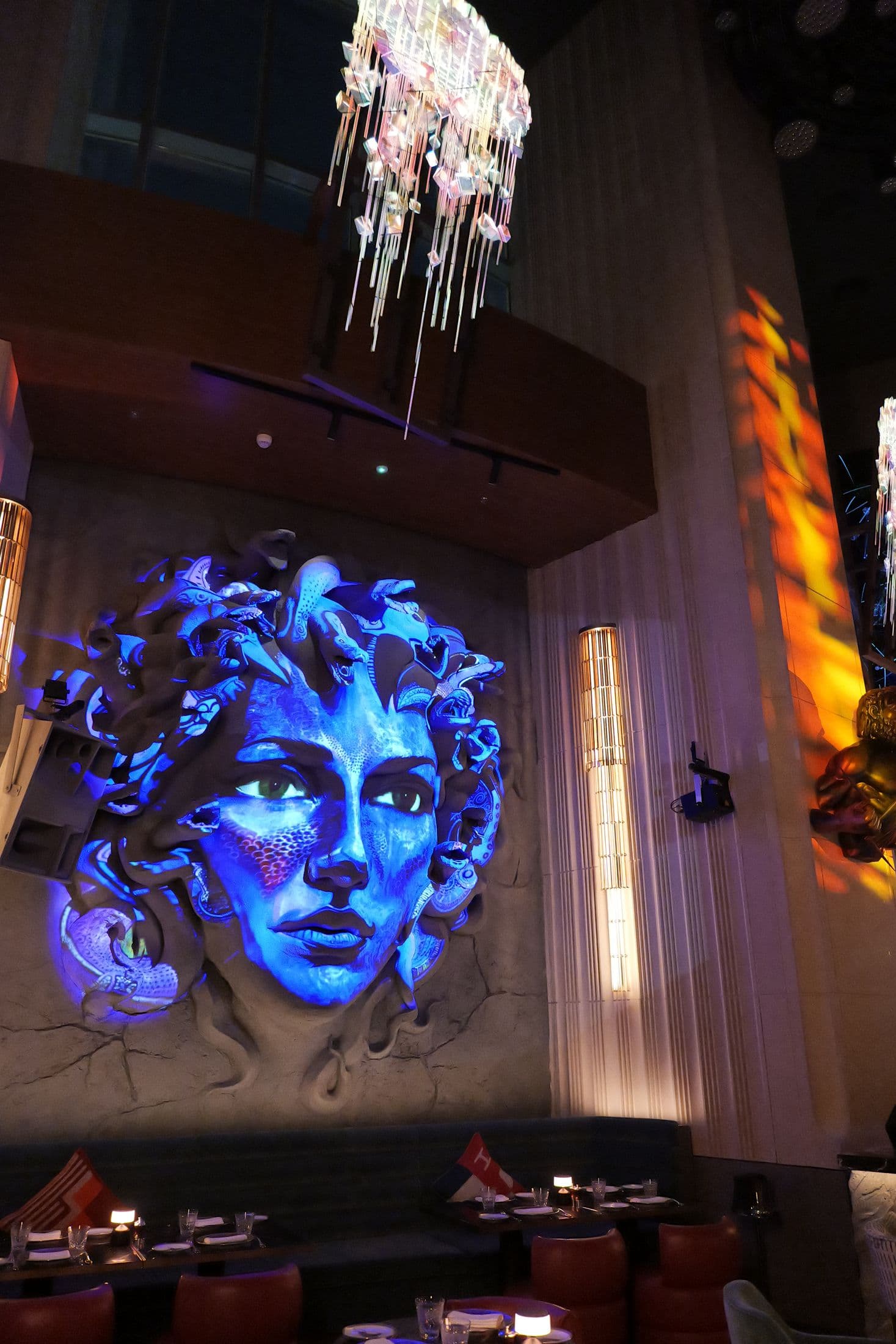 A projection-mapped relief lit in blue above the lounge at ZENON, beside a column of warm light