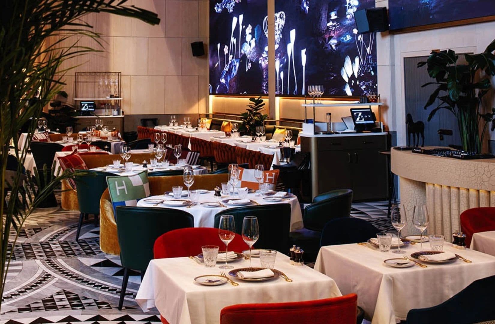 Tables laid for dinner in the ZENON dining room, under a wall of immersive screens